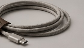 A braided USB-C cable coiled with a leather strap beside uGOvu Core